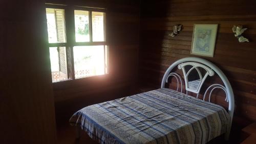 1 dormitorio con 1 cama en una habitación con 2 ventanas en Sitio do Espigão en Viamão
