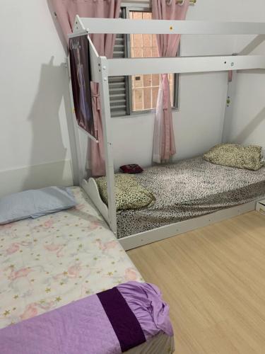 a bedroom with a bunk bed and a window at Casa com churrasqueira Guilhermina Praia Grande in Praia Grande