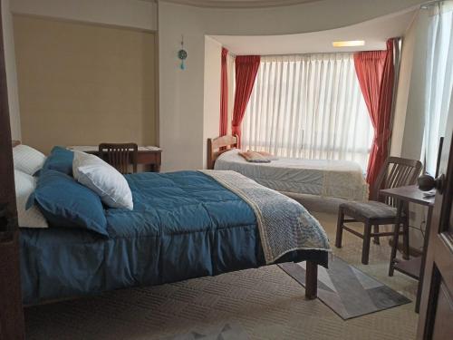 a bedroom with two beds and a table and chairs at Apartamento, cómodo, en el corazón de Cochabamba in Cochabamba