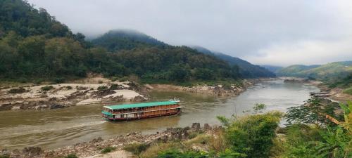 un barco en un río en las montañas en Mekong Backpackers, en Pakbeng