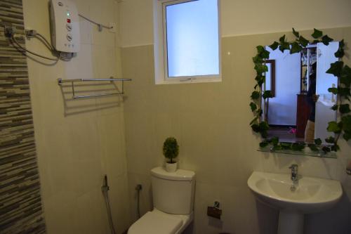 a bathroom with a toilet and a sink and a window at Infinity Condos by Lake Infinity in Nuwara Eliya