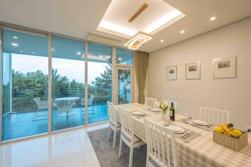 a dining room with a table and chairs and a balcony at 500m2 Busan Ocean view private Let house 부산 오션뷰 3개층 대저택 독채펜션 렛하우스 in Busan