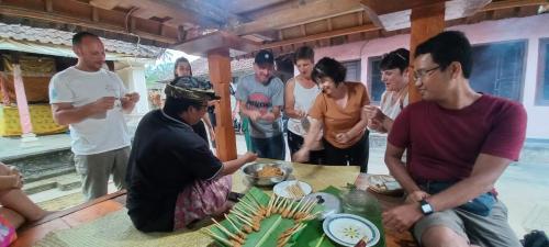 a group of people standing around a table with food at Pinge Traditional Village in Petang
