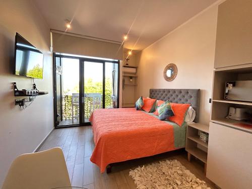 a bedroom with a bed with orange sheets and a balcony at LOFT 31 Villa Alemana BEEHOUSE in Villa Alemana