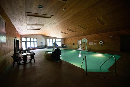a swimming pool in a building with a table and chairs at Whitetail Lodge in Saint Germain