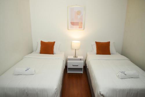 two twin beds in a small room with a lamp at Cozy Place in Bogotá