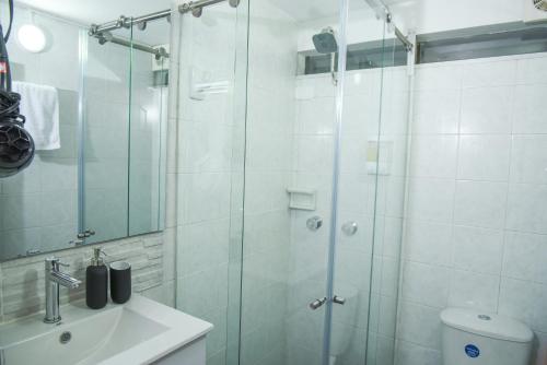 a bathroom with a glass shower and a sink at Cozy Place in Bogotá