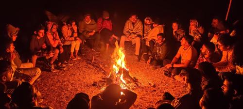 a group of people sitting around a fire at Yuva Yatri Campsite in Mahabaleshwar