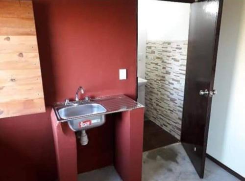 uma casa de banho com um lavatório e uma parede vermelha em Cabaña de Madera, El Pochote em San Andrés Huayapan