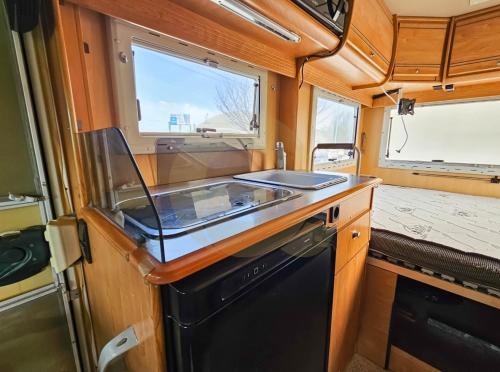 a kitchen in an rv with a sink and a stove at Sempre pronta para férias in Amadora