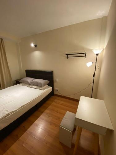 GN Homestay Miri في ميري: غرفة نوم بسرير وطاولة ومصباح