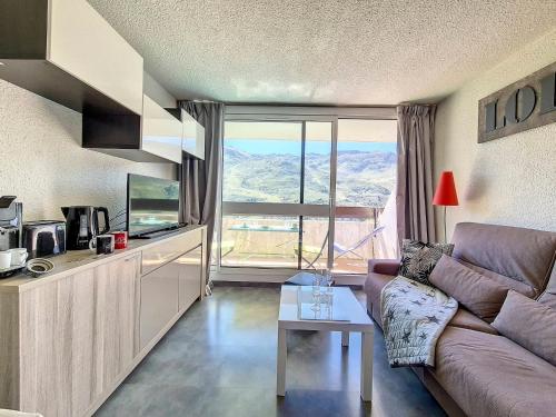 un salon avec un canapé et une grande fenêtre dans l'établissement Studio rénové - Pied des pistes, balcon sud - FR-1-344-1193, aux Menuires