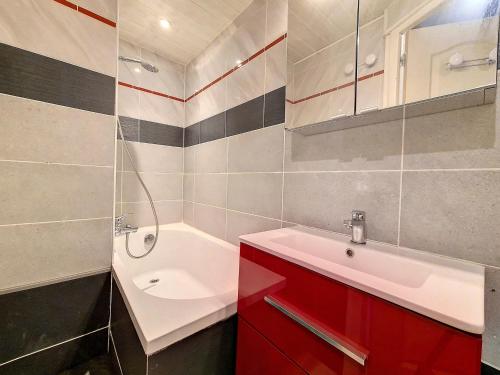 La salle de bains est pourvue d'une armoire rouge et d'un lavabo. dans l'établissement Appartement lumineux 5 pers · Pied des pistes · Balcon sud · 2 flocons Argent - FR-1-344-1200, aux Menuires