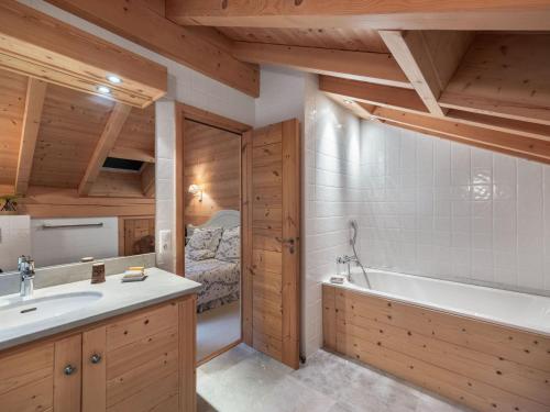 ein Badezimmer mit Badewanne und Waschbecken und ein Bett in der Unterkunft Chalet spacieux pour 14 personnes avec sauna et parking à Méribel - FR-1-566-65 in Les Allues