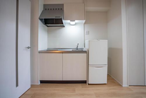 uma cozinha com um frigorífico branco e um lavatório em 震雲マンション103 em Osaka