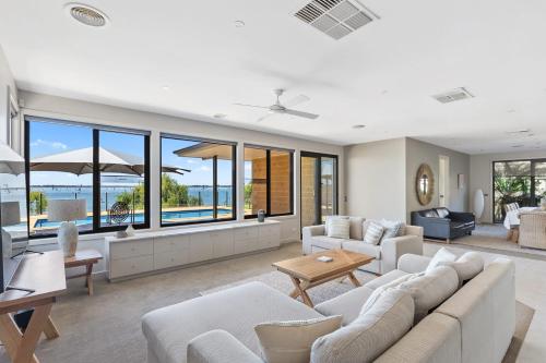 Una sala de estar con muebles blancos y grandes ventanales. en The Lakehouse on Rosemary, en Yarrawonga