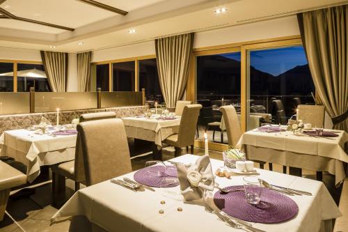a restaurant with white tables and chairs and windows at Astor Hotel in Schenna