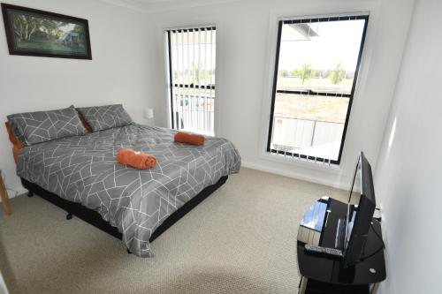 a bedroom with a bed with orange pillows and a suitcase at Ascot Gardens Serviced Apartments in Dubbo