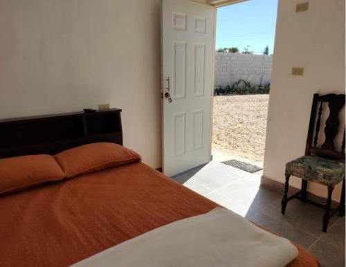 1 dormitorio con 1 cama y puerta con silla en Posada San Carlos en San Carlos
