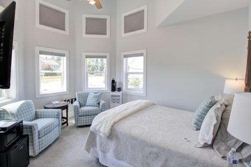 a bedroom with a bed and a chair and windows at Anchorage Inn in Coupeville