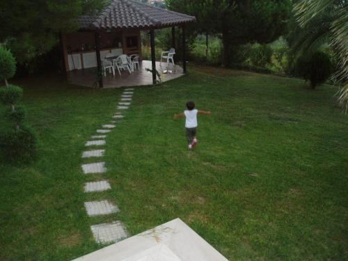 a girl walking down a path in a yard at Villa Anna Maria in Kriopigi