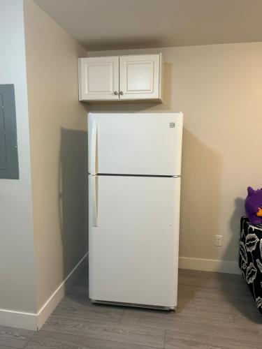 a white refrigerator in the corner of a room at A Comfortable 1Bedroom Suit with Seperate Entrance in New Westminster