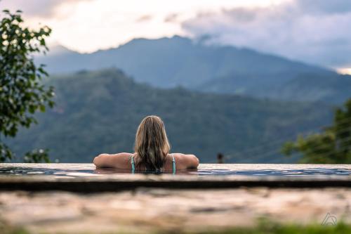 uma mulher sentada numa piscina a olhar para as montanhas em Awesome Place em Ella