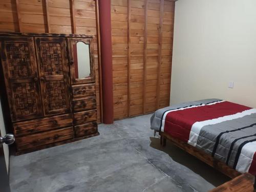 - une chambre avec un lit et un mur en bois dans l'établissement Cabaña de Madera, El Pochote, à San Andrés Huayapan