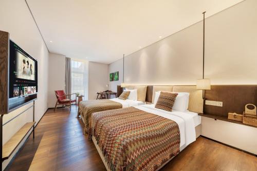 a hotel room with two beds and a flat screen tv at Wuyu Hotel - Chongqing Jiangbei Airport & Light Rail in Chongqing