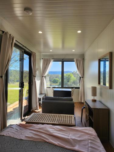a bedroom with a bed and a couch and windows at Delightful Container House with Views in Hartley