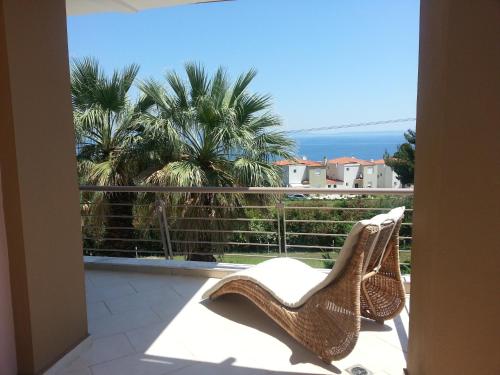a view of a balcony with a chair and palm trees at Villa Anna Maria in Kriopigi