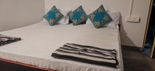 a white bed with blue pillows and a blanket on it at COCKS TOWN in Arambol