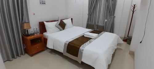 a bedroom with a large bed and a night stand at Khách sạn 68 ĐỒNG HẢI in Dong Hoi