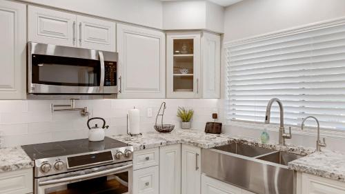 a white kitchen with a sink and a microwave at Luxe Central Scottsdale 4 bdrm w Backyard Oasis in Scottsdale