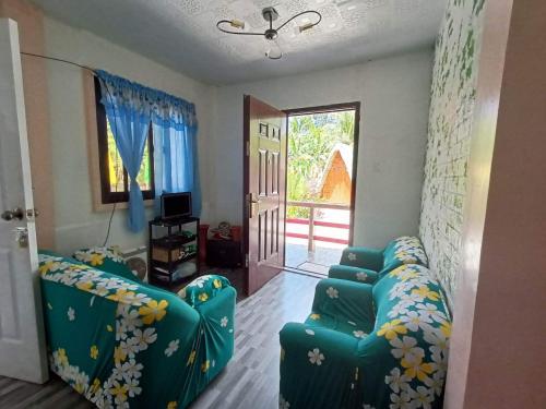 ein Wohnzimmer mit zwei blauen Sofas und einem TV in der Unterkunft Jodels Paradise in Ligao