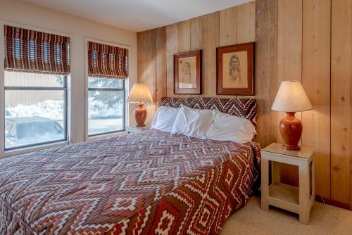 ein Schlafzimmer mit einem Bett, zwei Lampen und zwei Fenstern in der Unterkunft Sawtooth Condo 25 - Corner Unit, Walk to Bald Mountain & Hot Tub Onsite in Ketchum