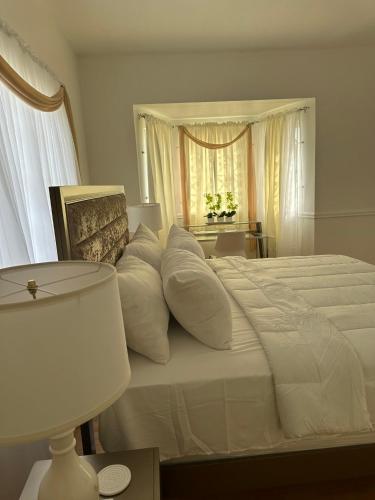 a white bedroom with a large white bed with pillows at Eagles Nest Villa House AC TV WIFI Fan Luxury Modern in Albion