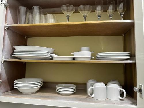 a cabinet filled with dishes and cups and plates at Eagles Nest Villa House AC TV WIFI Fan Luxury Modern in Albion
