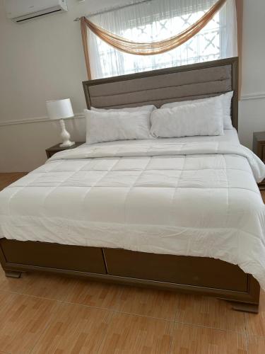 a bedroom with a large white bed with a window at Eagles Nest Villa House AC TV WIFI Fan Luxury Modern in Albion