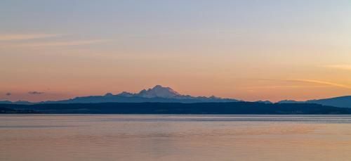 a sunset over the water with mountains in the background at Anchorage Inn in Coupeville