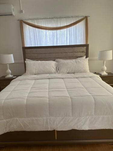 a bedroom with a large white bed with two lamps at Eagles Nest Villa House AC TV WIFI Fan Luxury Modern in Albion
