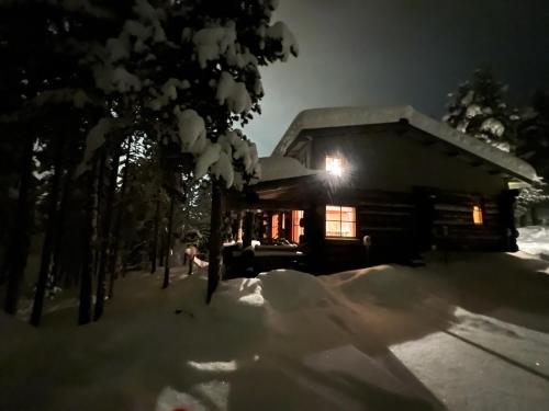 uma cabana de madeira na neve à noite em Rauhallinen kelohuoneisto lähellä palveluita, Peacefull Log apartment at Ylläs em Ylläsjärvi
