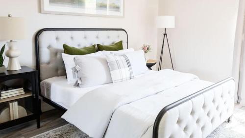 een wit bed met witte lakens en groene kussens bij Stylish Old Town 2 bdrm ground floor Condo in Scottsdale