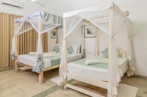 two beds in a room with two canopy beds at Aurora in Unawatuna