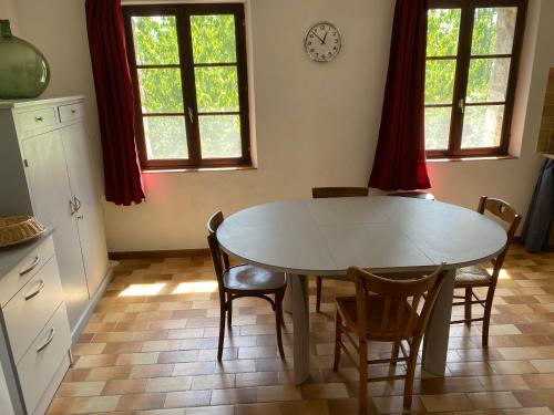 una cocina con mesa y sillas y un reloj en la pared en Ferme de Fonfroide Location à la semaine en La Motte-Chalançon