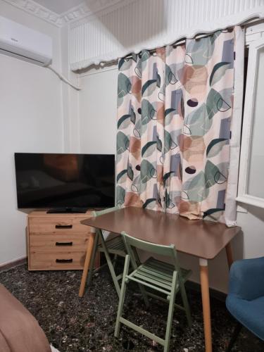 una mesa y una silla en una habitación con TV en Peace'nQuiet - 200m Nikaia Metro - Detached House with Terrace, en Pireo