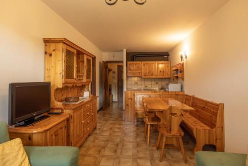 una cucina con armadi in legno e un tavolo con televisore di Casa alla Sorgente, con vista panoramica a San Vito di Cadore