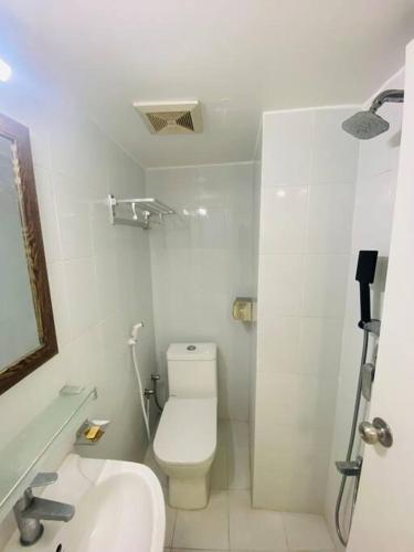 a white bathroom with a toilet and a sink at Cozy Studio Apartment Basundhara in Dhaka