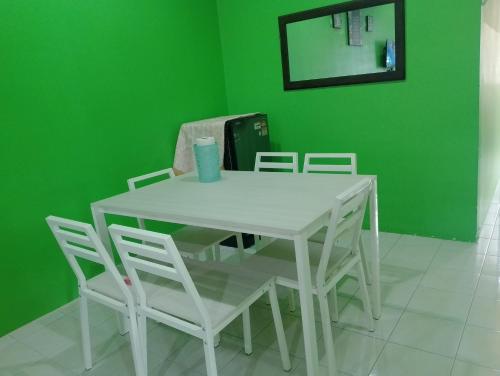 uma mesa branca e cadeiras num quarto com uma parede verde em Irman Homestay Pendang em Pendang