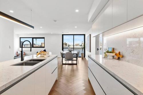 a kitchen with white cabinets and a living room at Hobart CBD Roof Top Penthouse in Hobart
